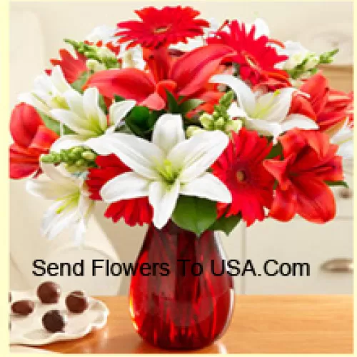 Rote Gerbera, weiße Lilien, rote Lilien und andere bunte Blumen, wunderschön in einer Glasvase arrangiert