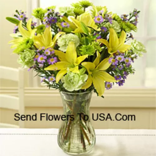 Gigli gialli e altri fiori assortiti disposti bellamente in un vaso di vetro