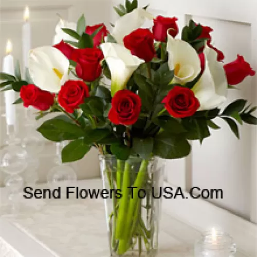 Rosas rojas y lirios blancos con algunos helechos en un jarrón de cristal