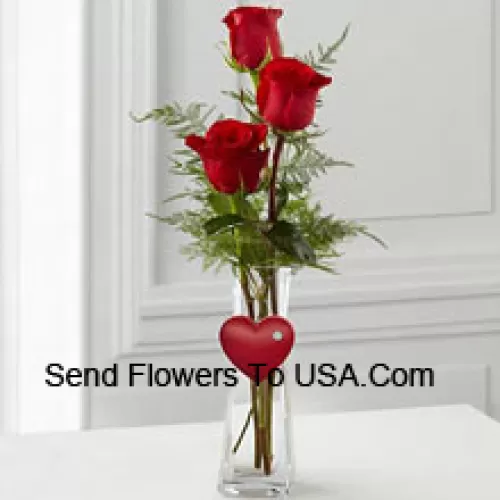 3 rote Rosen in einer Glasvase mit einem kleinen Herz daran befestigt
